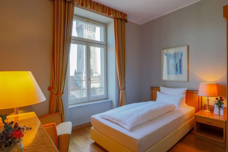 standard single room plus with a wide bed, spacious wardrobe, desk and armchair