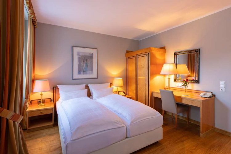 standard double room with a wide bed, spacious wardrobe, desk and armchair