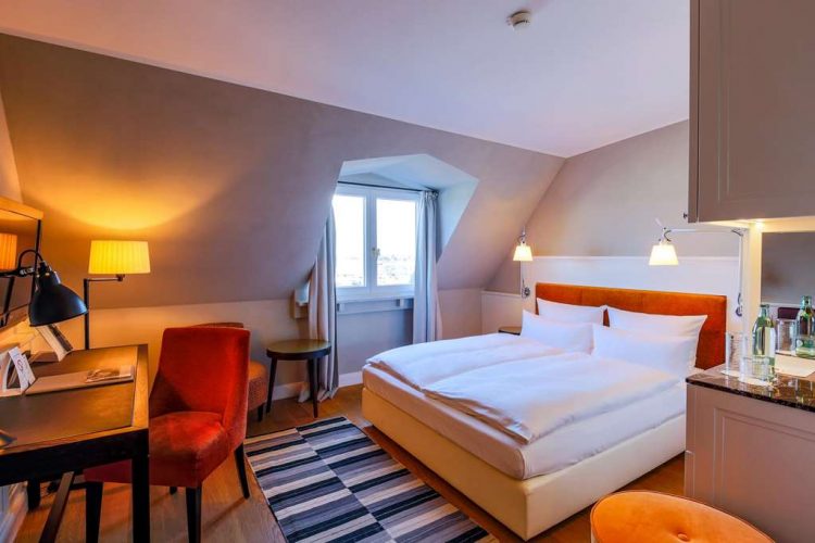 Double room superior plus with a wide bed, wardrobe, armchair and lake view