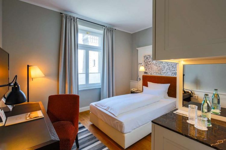 Single room superior plus with a wide bed, wardrobe, armchair, desk and lake view